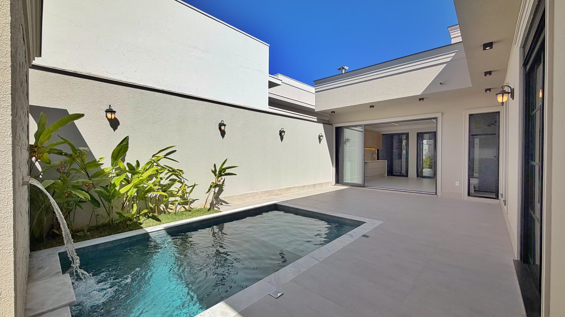Piscina com cascata e integração com a área gourmet envidraçada