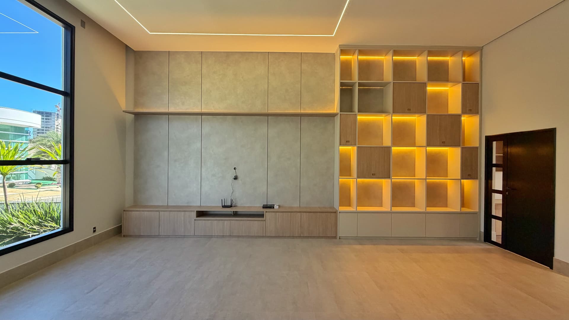 Sala de estar com painel de TV e nichos com iluminação embutida