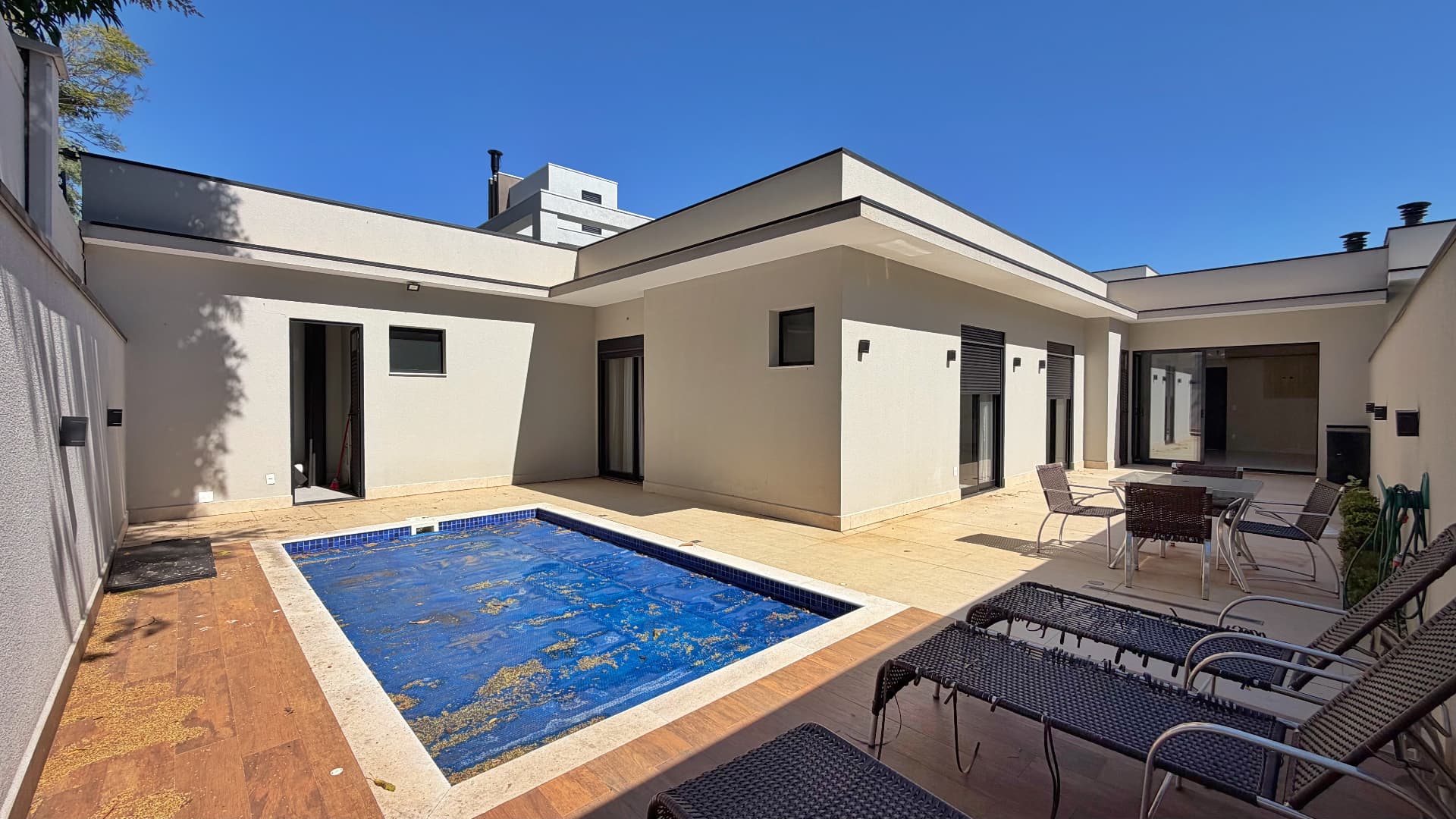 Vista ampla da piscina com a casa ao fundo em dia ensolarado
