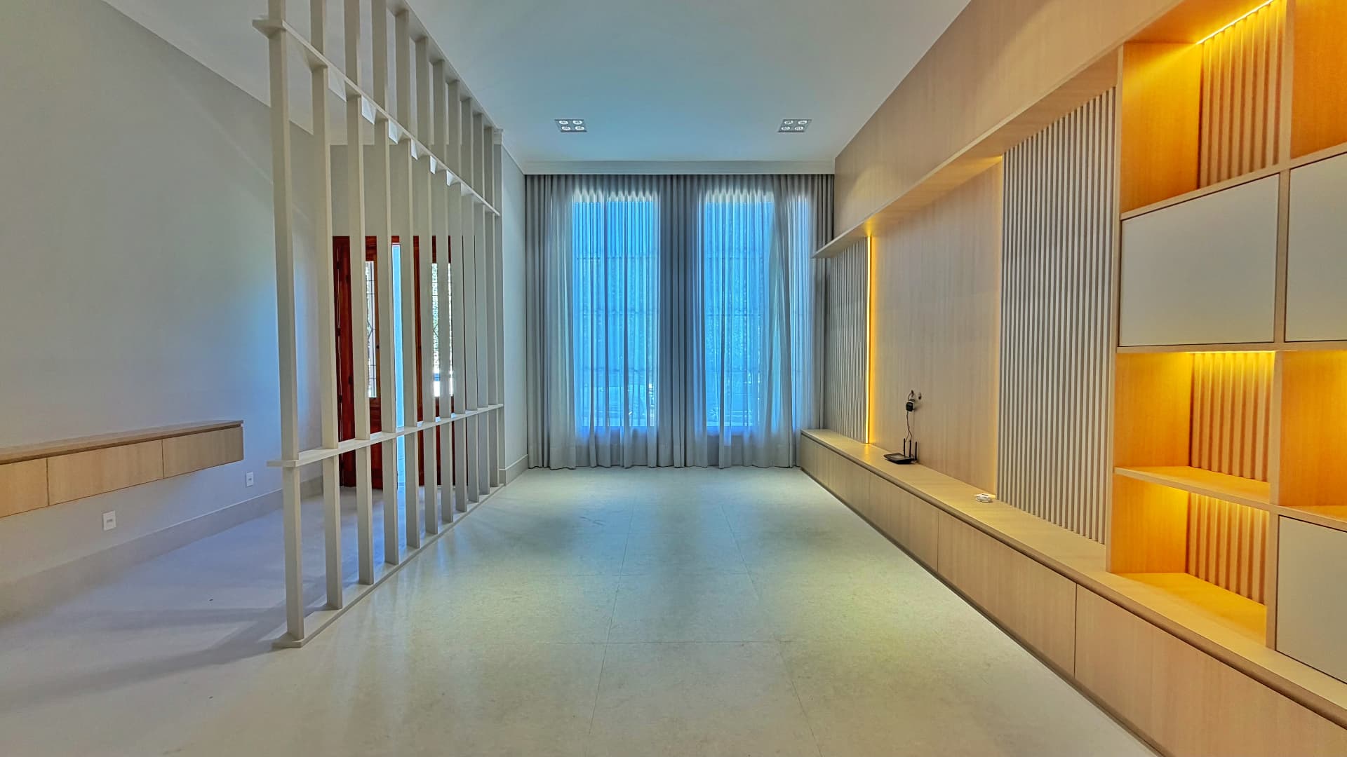 Sala de estar com cortinas, janelas altas e marcenaria planejada