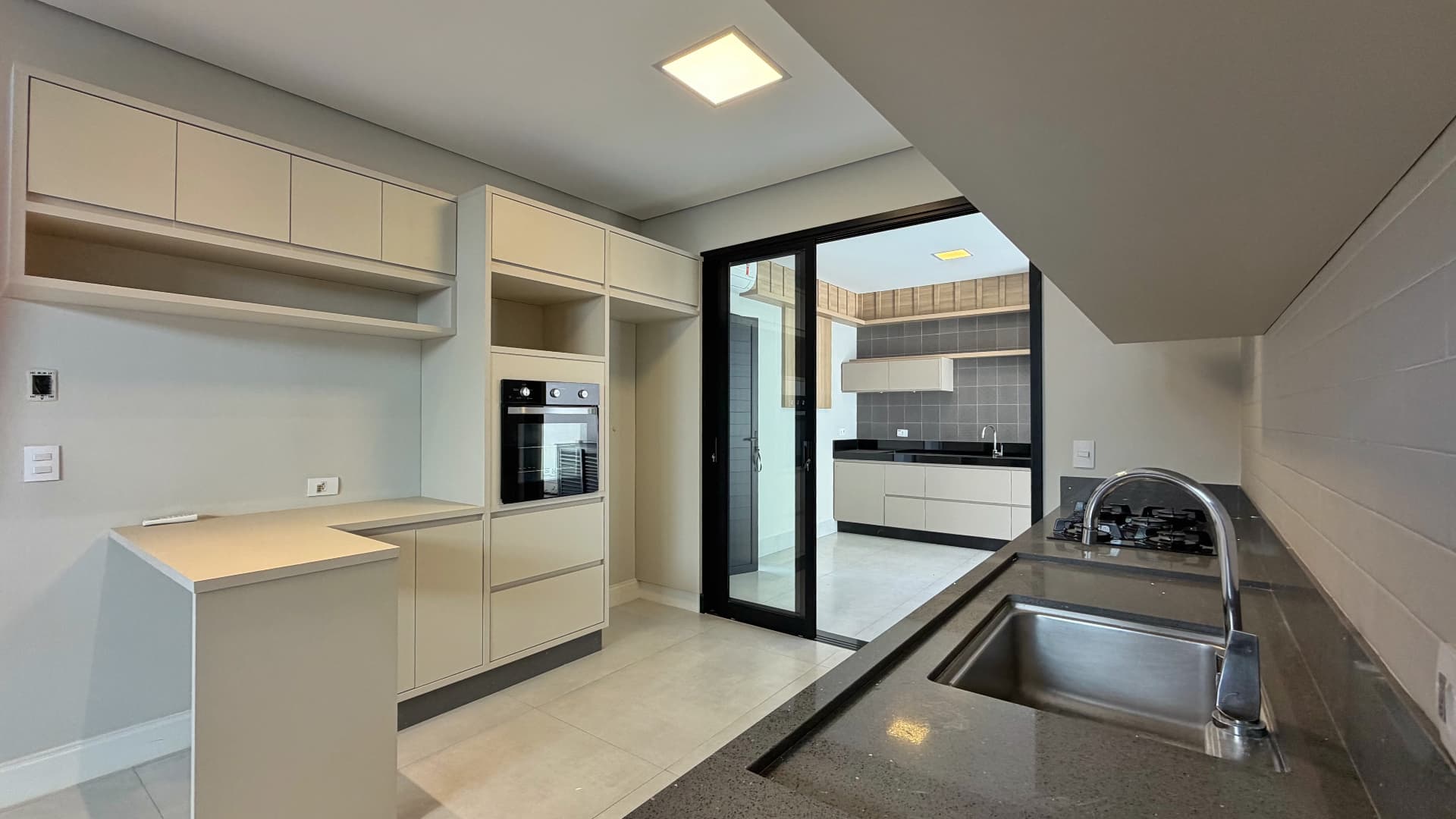 Detalhe da cozinha com cooktop e acesso à área de serviço
