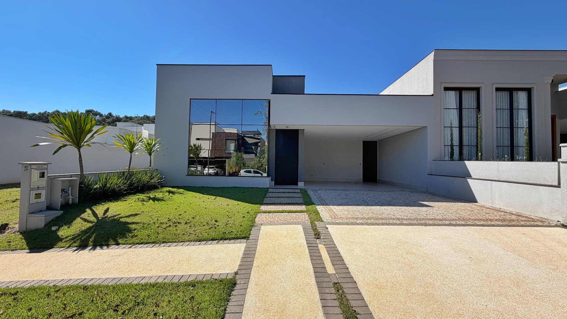 Fachada da Casa D36 com garagem coberta e jardim gramado