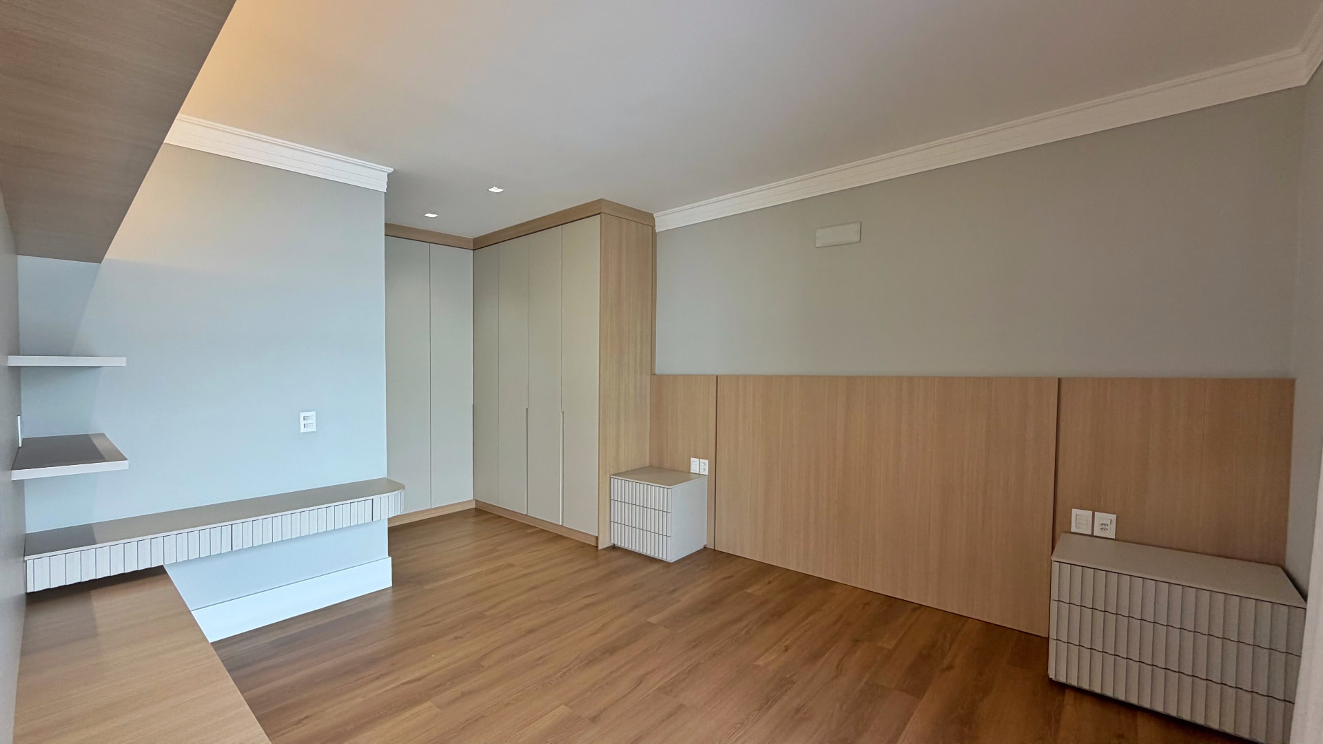 Suíte master com painel de madeira, armários planejados e piso laminado