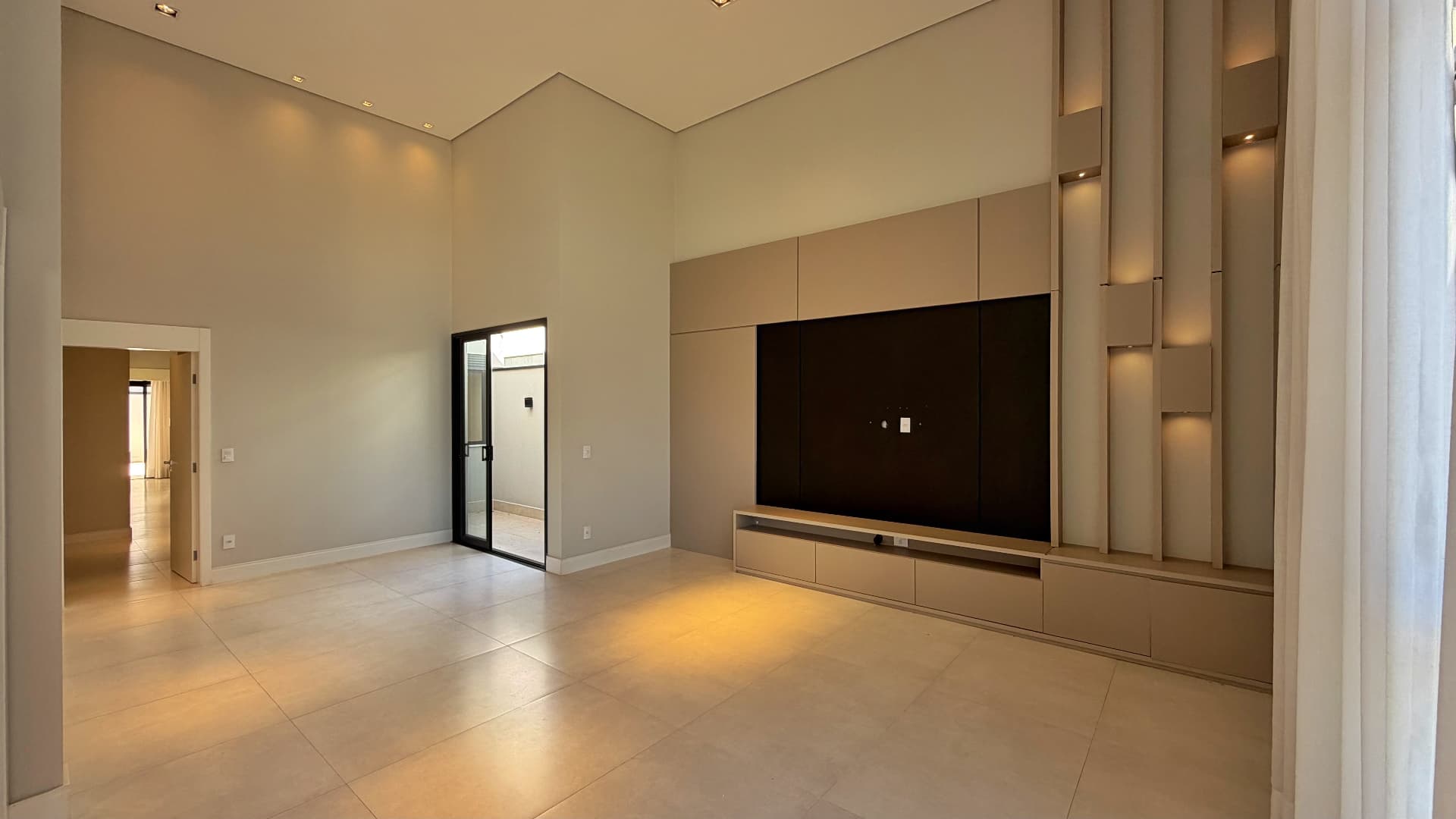 Sala de estar com pé-direito alto e painel de TV