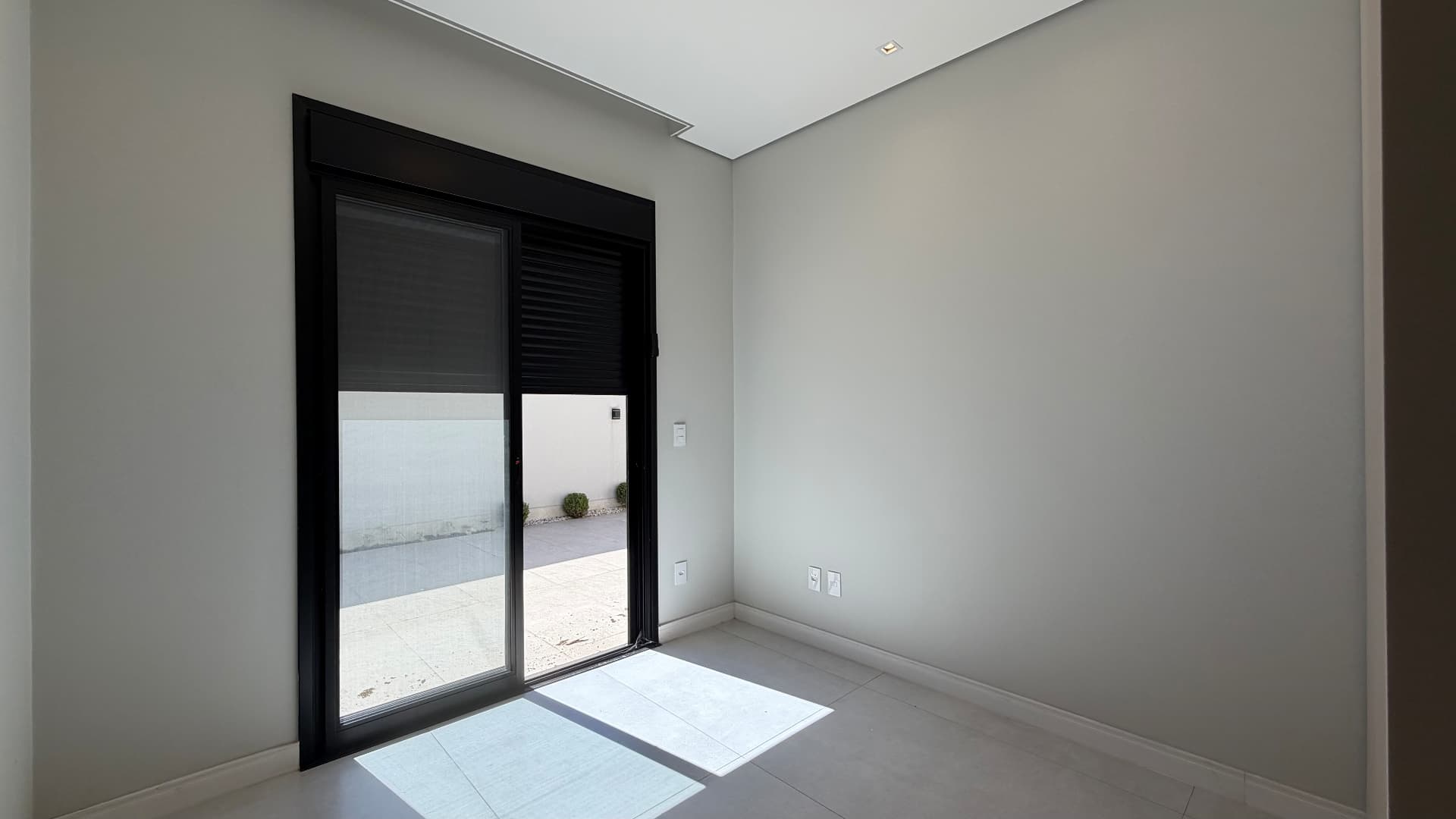 Quarto com porta de vidro e saída para a área externa