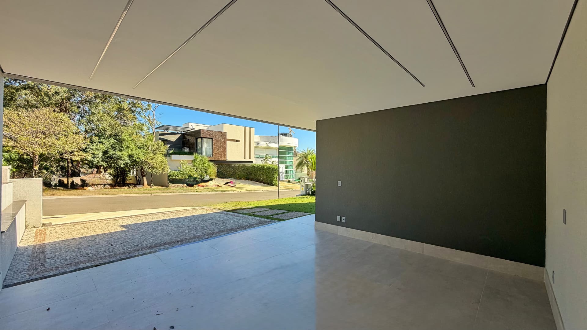 Garagem coberta com vista para a rua arborizada do condomínio