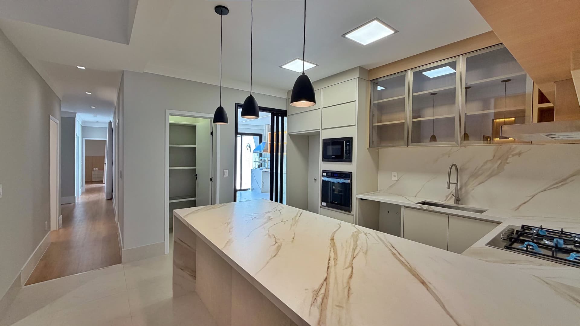 Bancada da cozinha em mármore com cooktop e acesso ao corredor