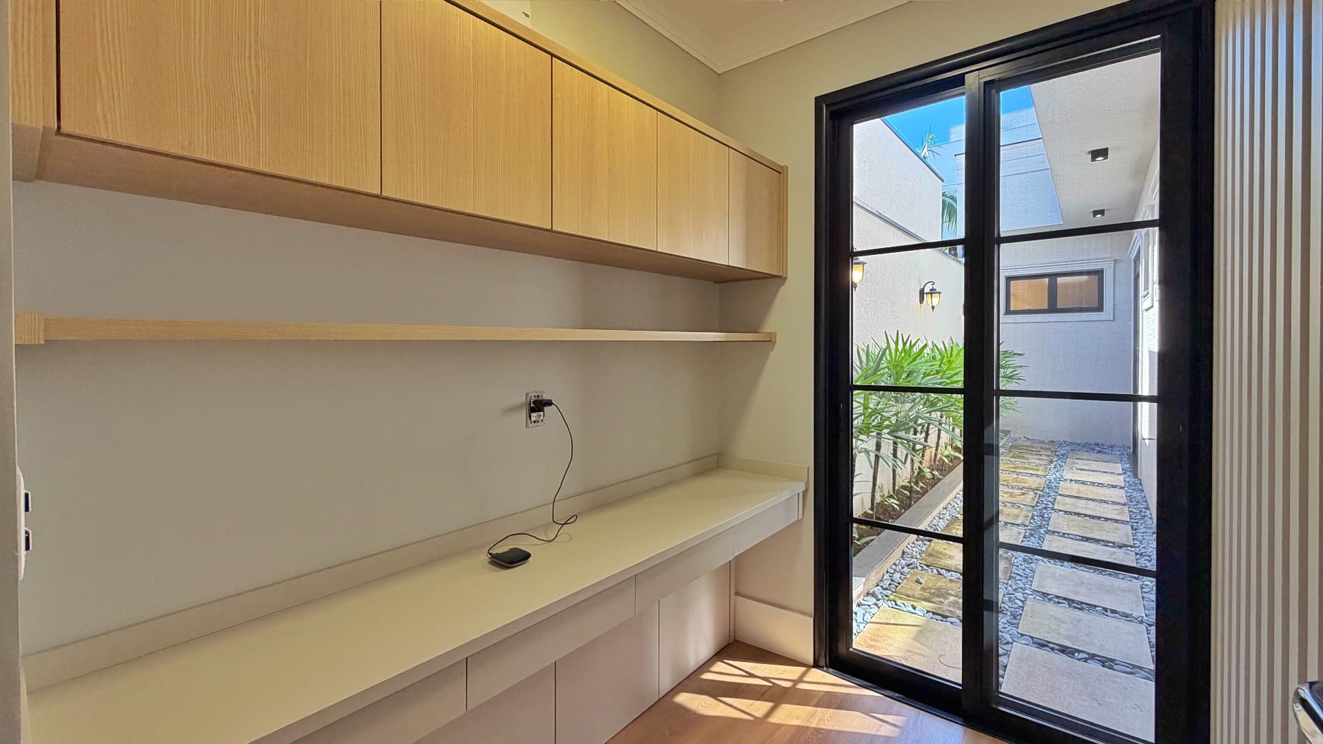 Home office com bancada planejada e vista para o jardim interno
