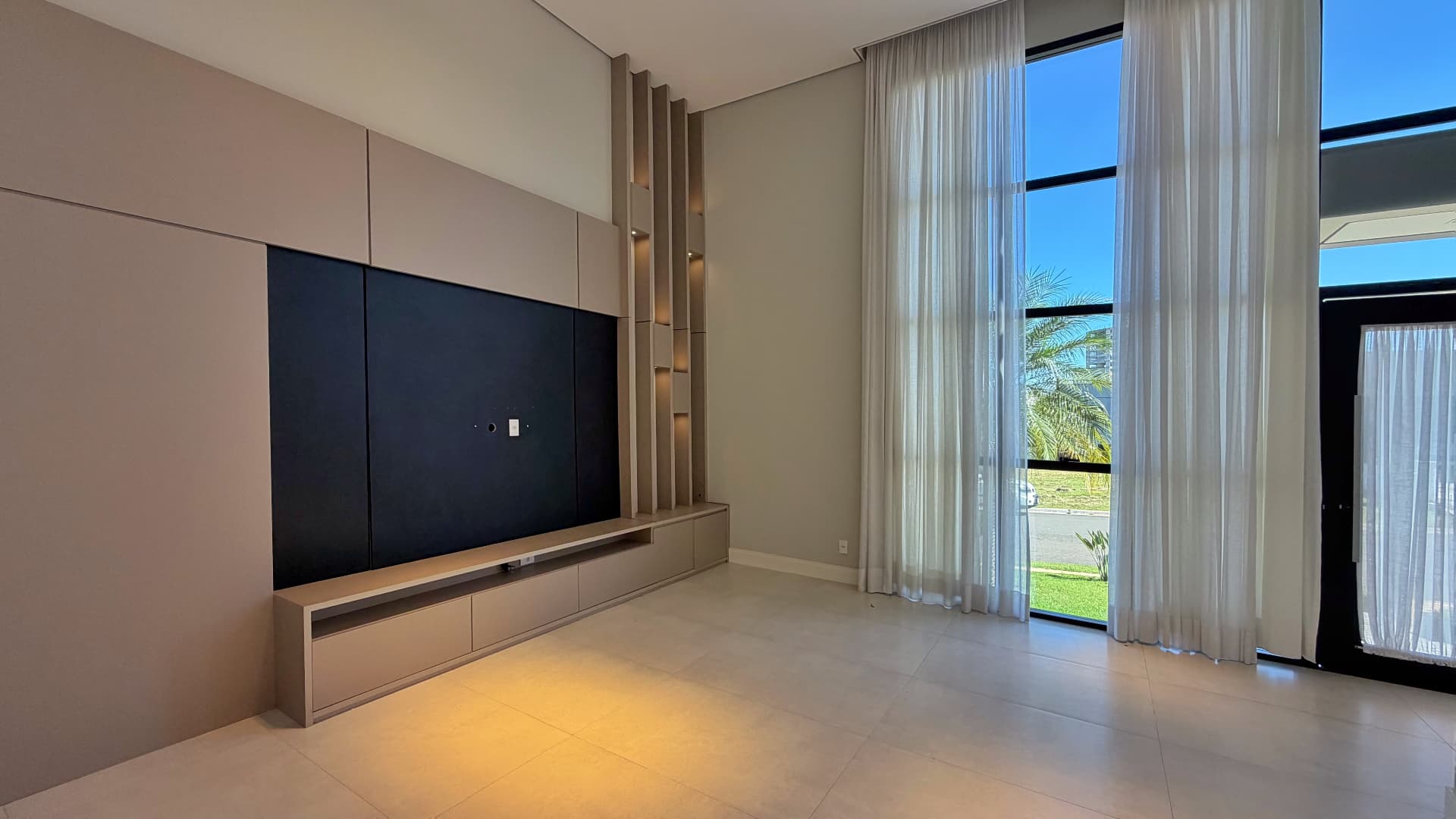 Sala com cortinas e janelas amplas até o teto