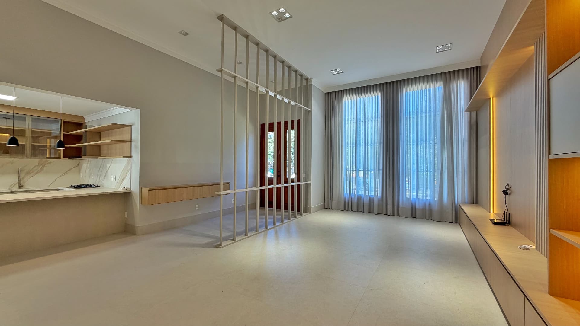 Sala de estar integrada à cozinha com brise vertical e cortinas