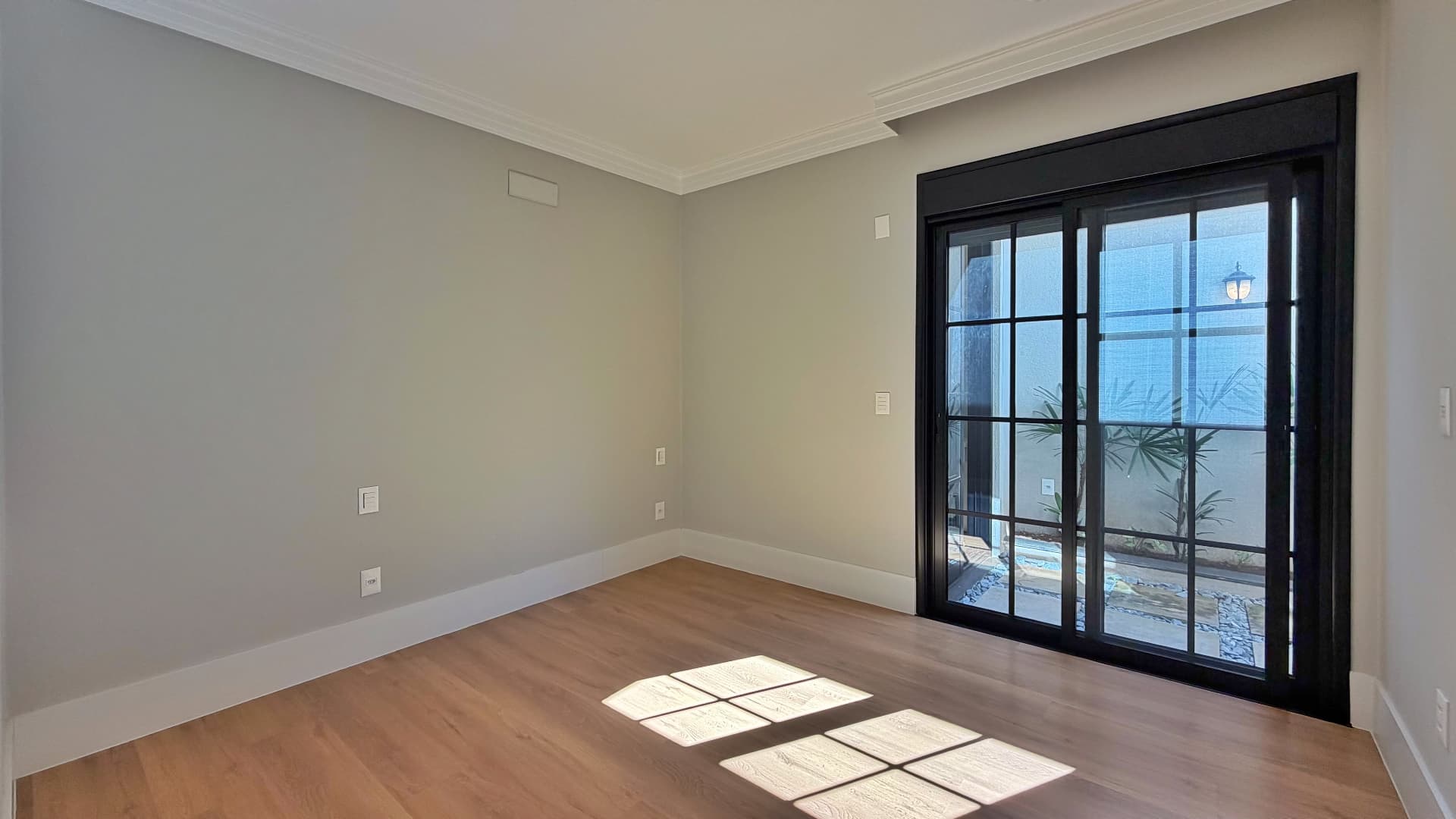 Suíte com piso laminado e porta de vidro para o jardim interno